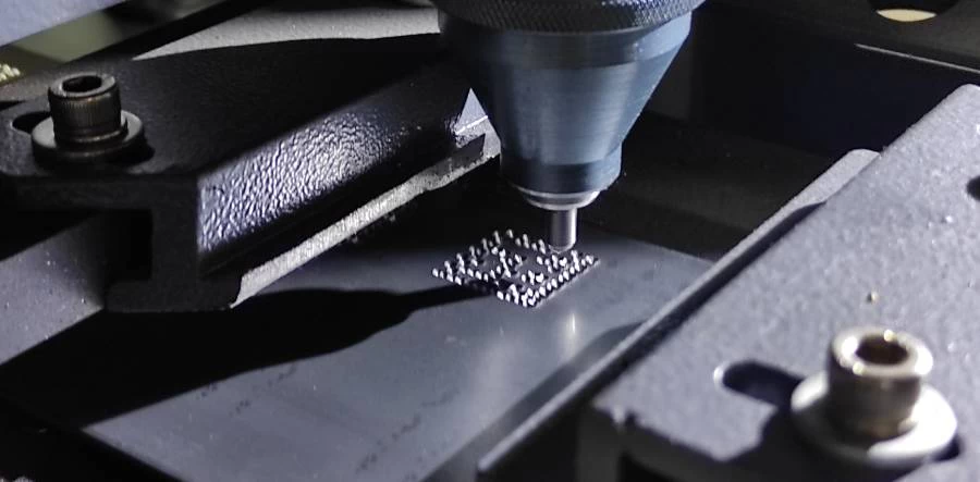 Close-up of a machine engraving a QR code on a metal tag, demonstrating precise beam marking by Guanda International Machinery.