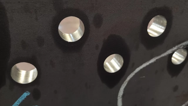Close-up of precisely drilled holes in a steel beam.