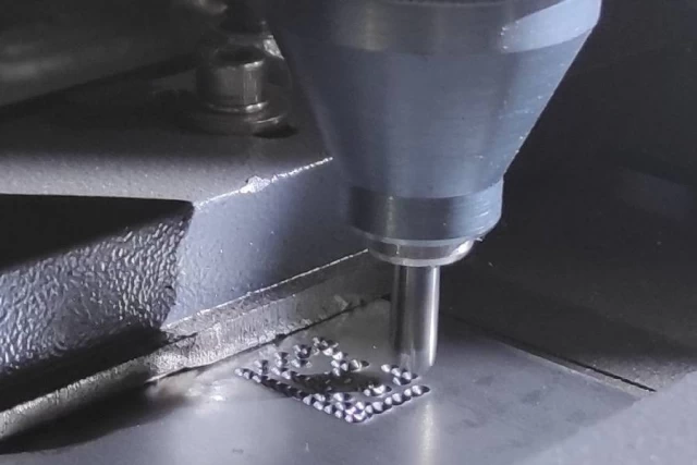 Close-up of the STM machine engraving steel tags, highlighting precision work by Guanda International Machinery." />